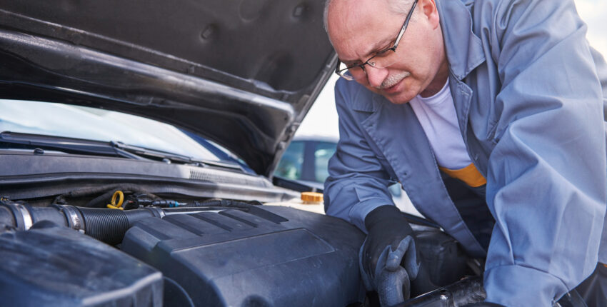 Expert mechanic inspecting engine for leaks
