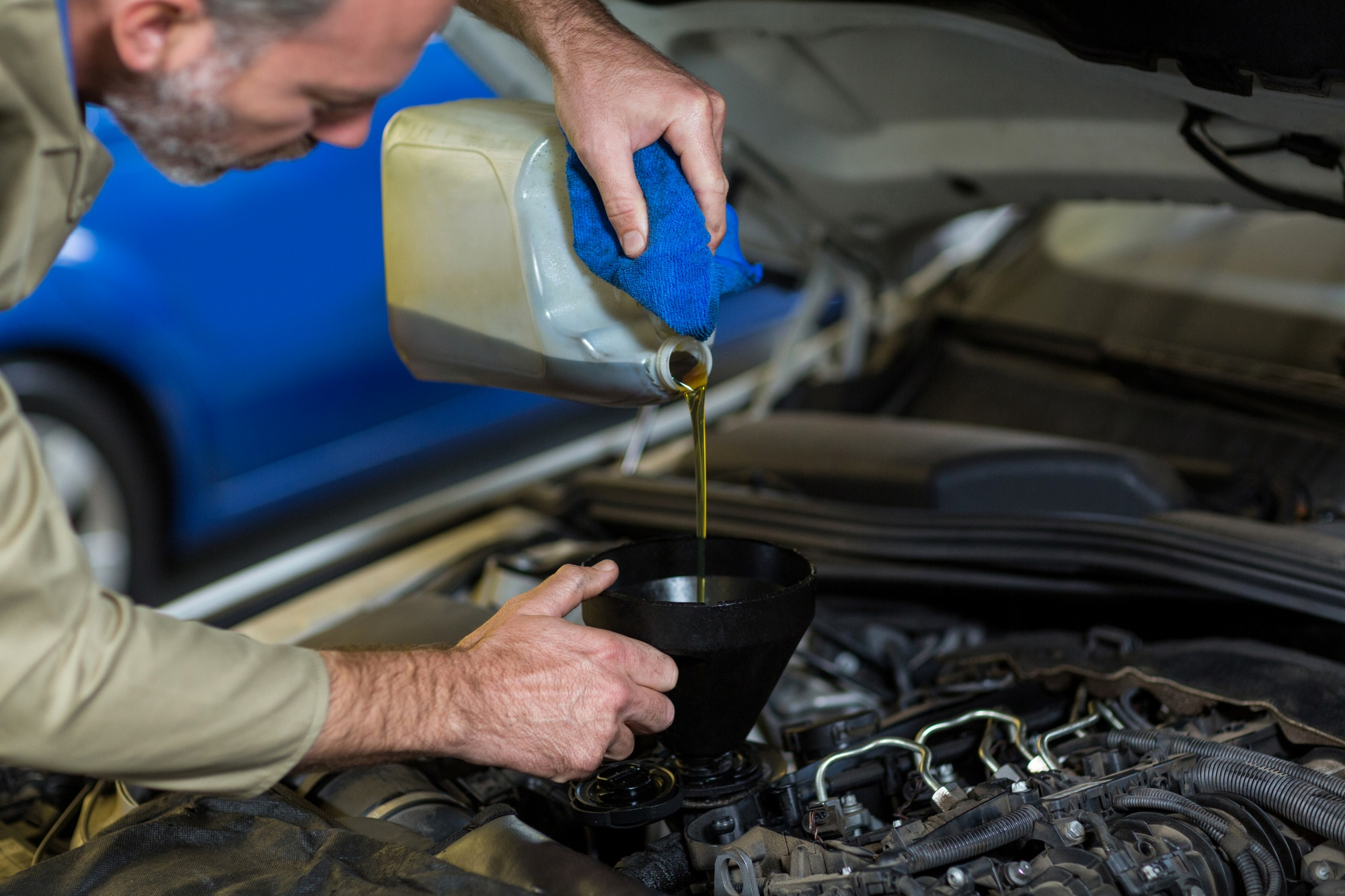 Mechanic pouring engine oil into vehicle
